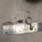 עגילי כסף בעבודת יד עם תליון פרידוט ירוק קטן התלוי על חוט כסף עד