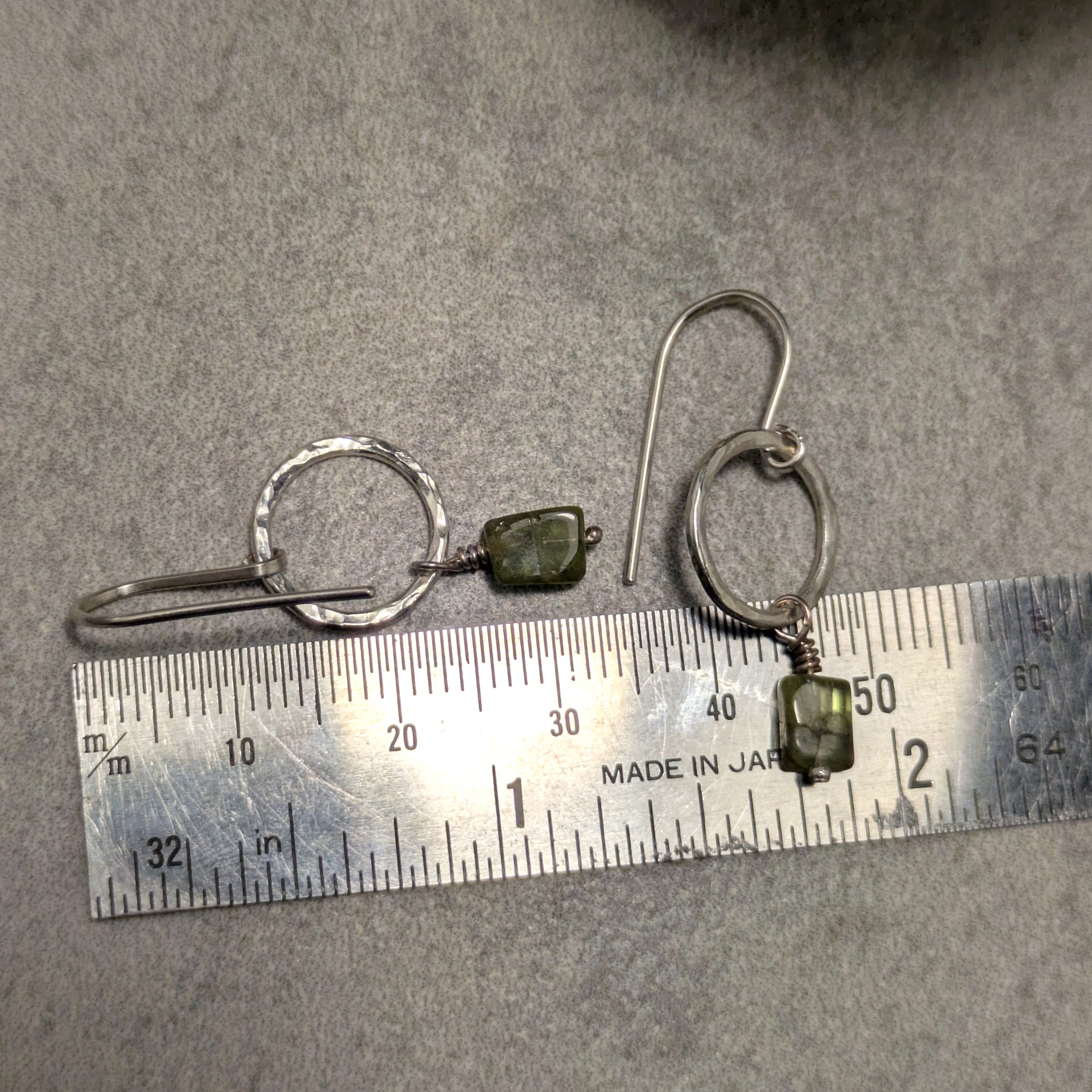 עגילי כסף בעבודת יד עם תליון פרידוט ירוק קטן התלוי על חוט כסף עד