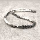   צ'וקר אבני חן עשוי בעבודת יד עם הולייט לבן, ג'ספר אפורה והמטייט שחורה, בעיצוב קצר ומודרני.